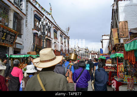 Pilgrims of Tibetan Buddhism, monks, locals, and tourists walking around Barkor, a popular devotional route around Jokhang Temple in Lhasa, Tibet Stock Photo