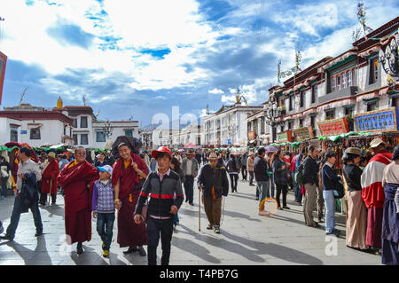 Pilgrims of Tibetan Buddhism, monks, locals, and tourists walking around Barkor, a popular devotional route around Jokhang Temple in Lhasa, Tibet Stock Photo