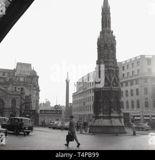 1960s, historical, cobbled forecourt and entrance to Charing Cross mainline railway Station on The Strand, London, England, UK. One can see the sign for the Strand Underground Station which was the name used for it at this time. It was not until the late 70s that the underground station was remamed 'Charing Cross'. Seen on the right of the picture is the monument, the Eleanor Cross designed by E. M Barry and erected in 1864. Stock Photo