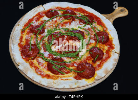 Thin crust beef pepperoni pizza with basil pesto sauce Stock Photo