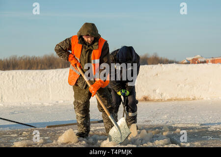 Workers clean ice hole cut in the river of ice Stock Photo