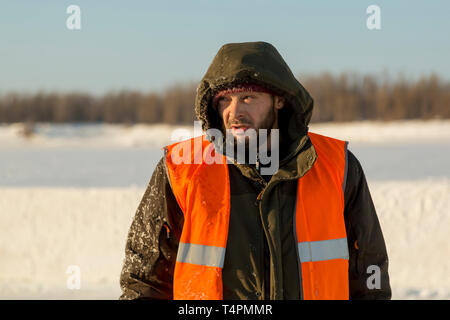The average plan of a worker with a hood on his head in an orange reflective vest Stock Photo