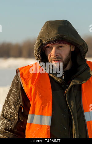 The average plan of a worker with a hood on his head in an orange reflective vest Stock Photo