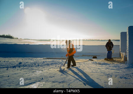 Portrait of a worker in an orange reflective vest snow shoveling on a river ice Stock Photo