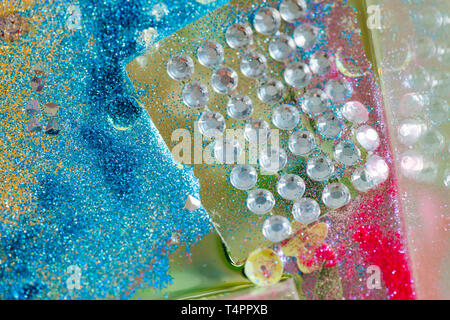 Beautifully sparkling. Decorative big crystals placed in a row and thrown in blue and pink glitter powder Stock Photo