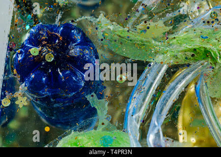 Causing global warming. Blue used plastic bottle immersed in dirty water with colorful harmful garbage Stock Photo