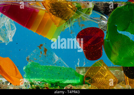 Immersing crumpled bottle. Disposal colorful plastic cups floating under water with broken plates and empty bottles Stock Photo