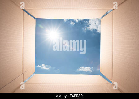 Blue sky viewed from inside of a cardboard box. Stock Photo