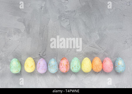 Pastel and gold colored eggs decoration on a gray background. Easter celebration concept. Top view, flat lay, copy space. Stock Photo