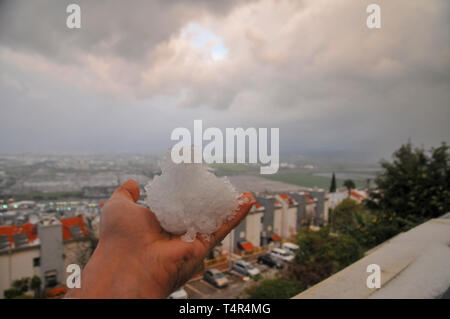 Hand holding hail after a hail storm, Photographed in Haifa, Israel in March Stock Photo