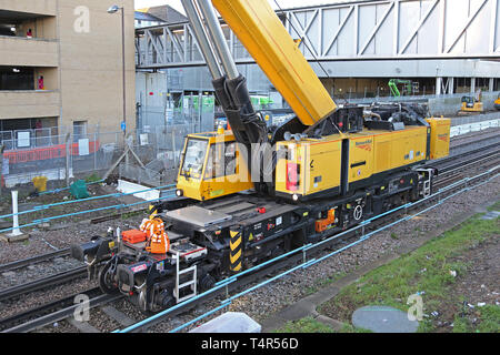 A railway-mounted Kirow crane lifts a temporary scaffolding footbridge into place at Feltham Station, Middlesex during a weekend railway closure. Stock Photo