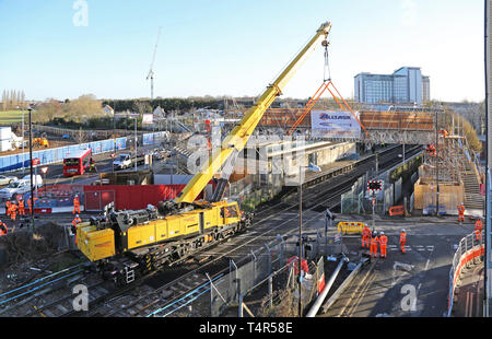 A railway-mounted Kirow crane lifts a temporary scaffolding footbridge into place at Feltham Station, Middlesex during a weekend railway closure. Stock Photo