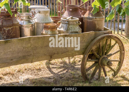 Old carriage with milk churns loaded as a decoration on a farm Stock Photo