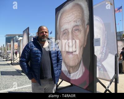 San Francisco, USA. 17th Apr, 2019. The photographer Luigi Toscano stands in front of the portrait of the Holocaust survivor Sol Farkas. Born in Romania, Farkas is now 100 years old and lives in San Francisco. He was deported to Auschwitz in 1944. Large-format pictures of Holocaust survivors taken by German-Italian photographer Luigi Toscano have been on display in a large square in front of San Francisco City Hall since Wednesday. (Zu dpa ''German photographer shows pictures of Holocaust survivors in the USA') Credit: Barbara Munker/dpa/Alamy Live News Stock Photo