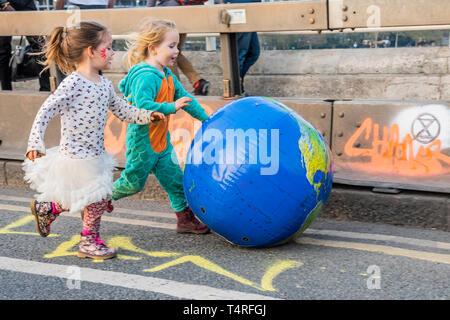 London, UK. 18th Apr 2019. Young children enjoy pushing an inflatable version of their world down the bridge - Evening and the festival atmosphere returns - Day 4 - Protestors from Extinction Rebellion block several junctions in London as part of their ongoing protest to demand action by the UK Government on the 'climate chrisis'. The action is part of an international co-ordinated protest. Credit: Guy Bell/Alamy Live News Stock Photo