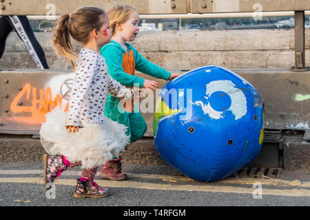 London, UK. 18th Apr 2019. Young children enjoy pushing an inflatable version of their world down the bridge - Evening and the festival atmosphere returns - Day 4 - Protestors from Extinction Rebellion block several junctions in London as part of their ongoing protest to demand action by the UK Government on the 'climate chrisis'. The action is part of an international co-ordinated protest. Credit: Guy Bell/Alamy Live News Stock Photo