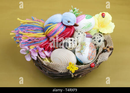 VILNIUS, LITHUANIA - APRIL 10, 2019: Traditional Lithuanian rural  homemade  wooden and plastic painted Easters eggs and bird  lie in basket nest on h Stock Photo