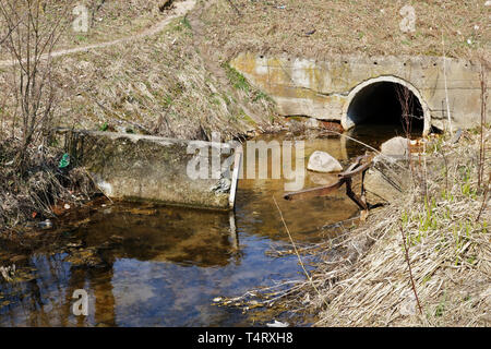 Dirty city waste  sewetr water merges into a clean forest  stream. Landscape concept - pollution of the environment Stock Photo