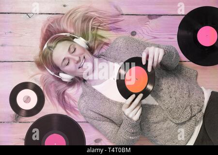 Young blond woman lying on the wooden floor, surrounded by records Stock Photo