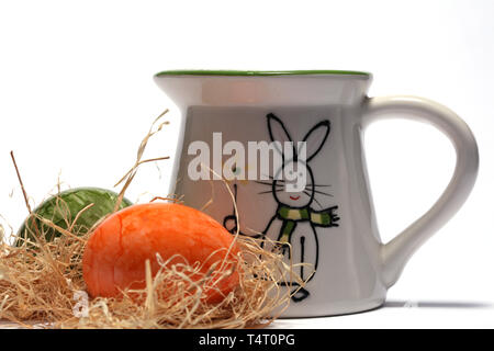 Easter jewellery with colorfully painted eggs and a milk jug with Easter motif Stock Photo