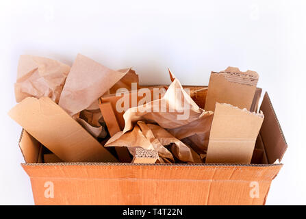 Cardboard box with crumpled paper and cardboard pieces against white background. Close-up. Stock Photo