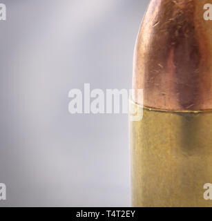 A 9mm bullet with a paper target in the background Stock Photo