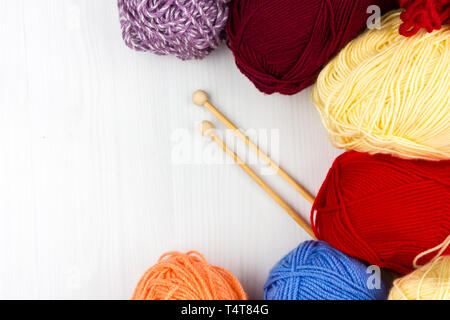 Flatlay of multicolored pastel knitting skeins of yarn and knitting needles on a white background Stock Photo