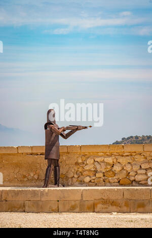 steel sculpture of medieval archer against blue sky above Santa Barbara Castle, Alicante spain Stock Photo