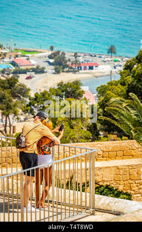 loving couple taking selfie in front of view of sea and town from santa barbara castle in alicante Spain Stock Photo