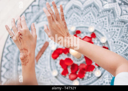 Dance of female hands with mehendi over the altar of candles and rose petals, women practices Stock Photo