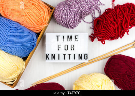Flatlay of multicolored pastel knitting skeins of yarn and knitting needles with lettering - Time to knitting Stock Photo