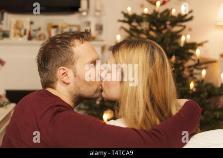 Young couple kissing in front of Christmas tree, Germany, Europe Stock Photo
