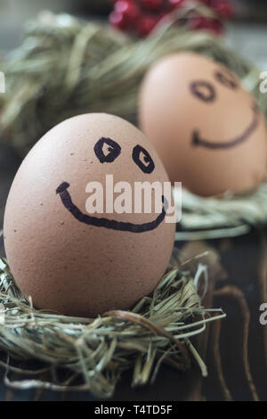 Close up of eggs with drawn funny faces on straw. Stock Photo