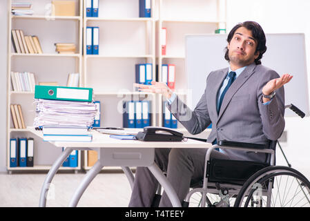 Young handsome employee in wheelchair at the office Stock Photo