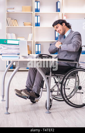 Young handsome employee in wheelchair at the office Stock Photo