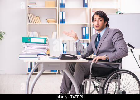 Young handsome employee in wheelchair at the office Stock Photo