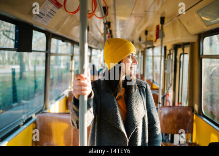 Young woman standing in a wagon of a driving tramway. Transportation, travel and lifestyle concept.