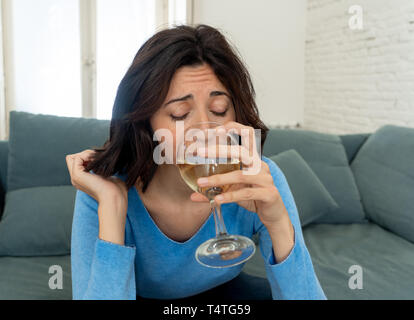 Portrait of depressed woman drinking glass of wine alone at home. Feeling distress, hopeless and frustrated, trying to feel better drinking. Unhealthy Stock Photo