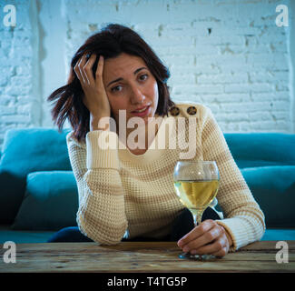 Portrait of depressed woman drinking glass of wine alone at home. Feeling distress, hopeless and frustrated, trying to feel better drinking. Unhealthy Stock Photo