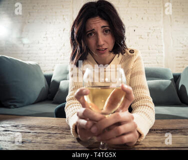 Portrait of depressed woman drinking glass of wine alone at home. Feeling distress, hopeless and frustrated, trying to feel better drinking. Unhealthy Stock Photo