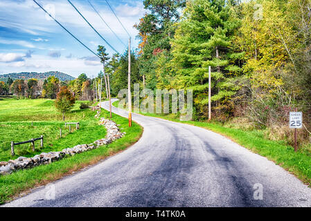A rural road by farm land within the new england town of cornwall connecticut on a blue sky day. Stock Photo