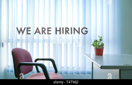 Job recruitment or hiring concept, office room scene with words We Are Hiring Stock Photo