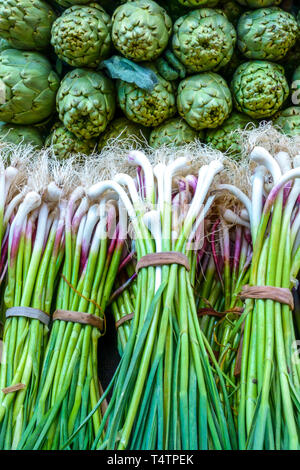 Fresh bundles of young garlic and green artichokes on display at a traditional farmers market in Valencia Stock Photo