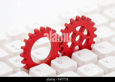 Two red gears on computer keyboard Stock Photo