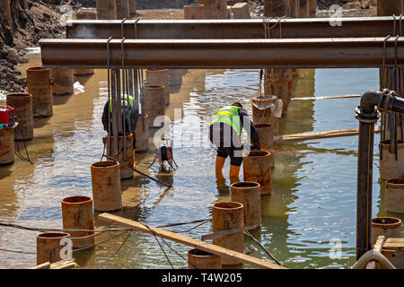 Welding and grinding in wet conditions. Abstract: Dangers of welding around water, not following standard safety procedure. Stock Photo