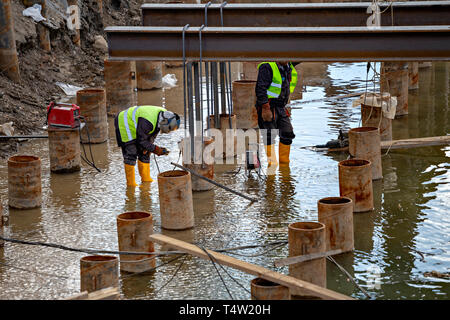 Welding and grinding in wet conditions. Abstract: Dangers of welding around water, not following standard safety procedure. Stock Photo