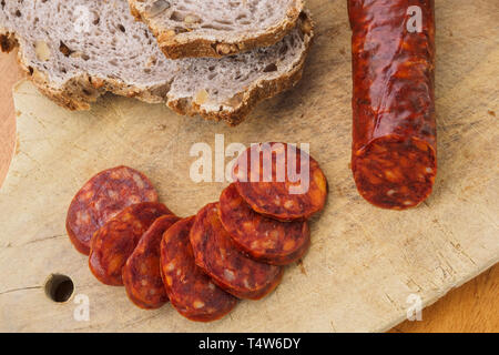 Iberian chorizo, Spanish chorizo or Spanish sausage cut into slices on a wooden board with rustic bread Stock Photo