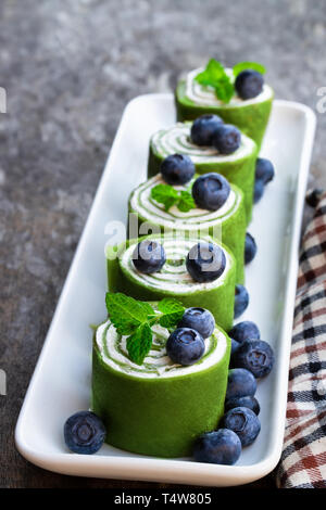 Matcha  green tea crepe with whipped cream and blueberry on wooden table Stock Photo