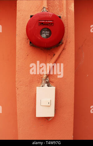 Red fire alarm on orange wall. Stock Photo