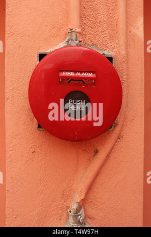 Red fire alarm on orange wall. Stock Photo